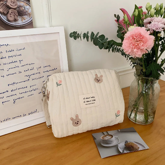 Trousse de toilette bébé - Complète et Pratique - rangement innovant - lapins - posée sur un bureau