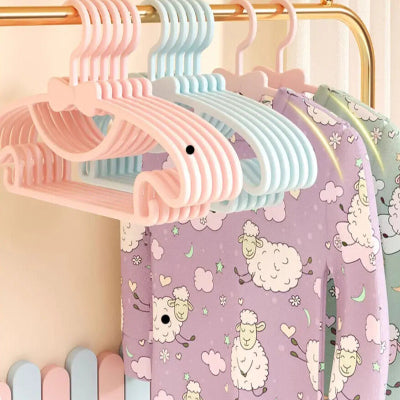 Cintre enfant plusieurs couleurs suspendus sur barre laiton horizontale portant pyjamas chambre enfant