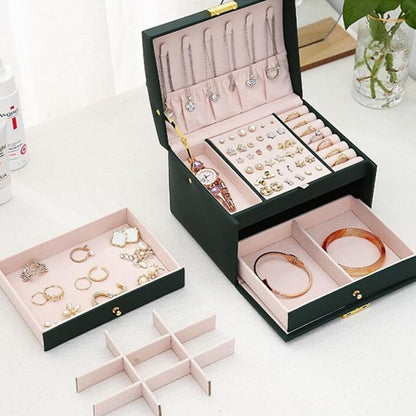Boite-a-bijoux-prestige-rangement-innovant-vert-ouverte-remplie-de-bijoux-posée-sur-une-table-blanche