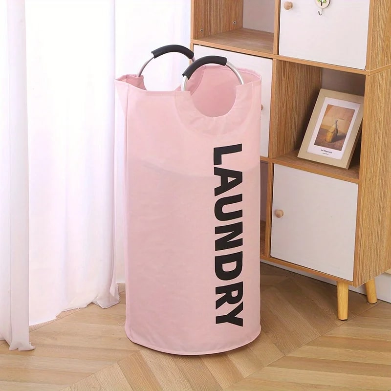 Panier-à-linge-pliable-spacieux-rangement-innovant-rose-posé-dans-le-salon