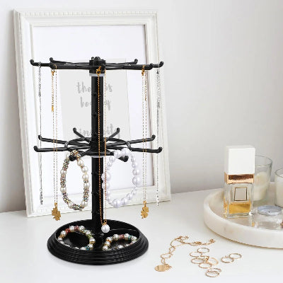 Porte bijoux  Élégant pratique noir deux niveaux rempli de bijoux posé sur surface blanche