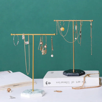 Porte bijoux Organisateur élégant blanc doré et noir doré portant des bijoux posés sur table blanche