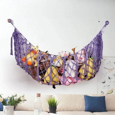 Rangement Peluche Coton Bohème violet rempli peluches accroché au mur dessus canapé