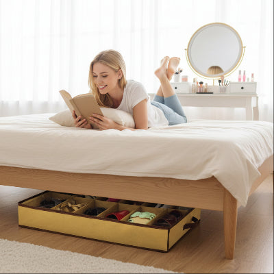Rangement chaussures sous lit placé sous le lit sur lequel allongée une jeune femme souriante lisant une livre
