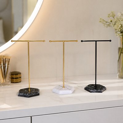 Porte bijoux noir blanc doré et noir doré posés sur table blanches