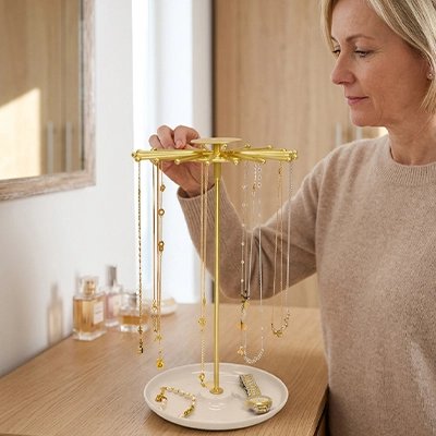 Porte bijoux portant des colliers et bagues devant une jeune femme blonde 