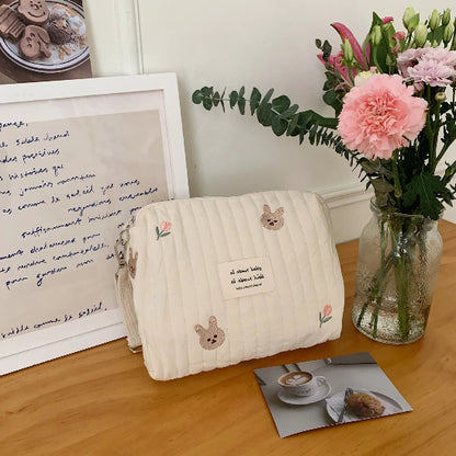 Trousse de toilette bébé - Complète et Pratique - rangement innovant - lapins - posée sur un bureau