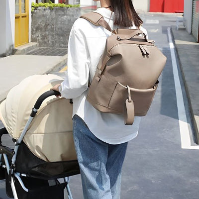 Sac à langer camel porté sur dos jeune maman poussant poussette