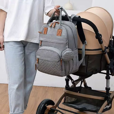 Sac à langer gris accroché sur poussette côté jeune maman