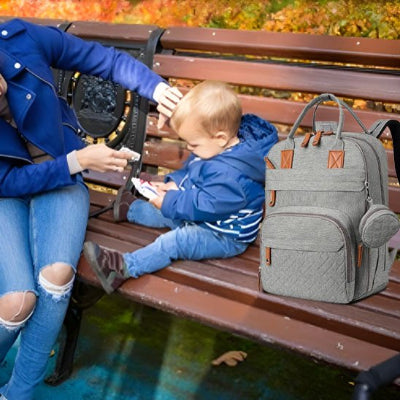 Sac à langer gris posé sur banc côté bébé et maman assis